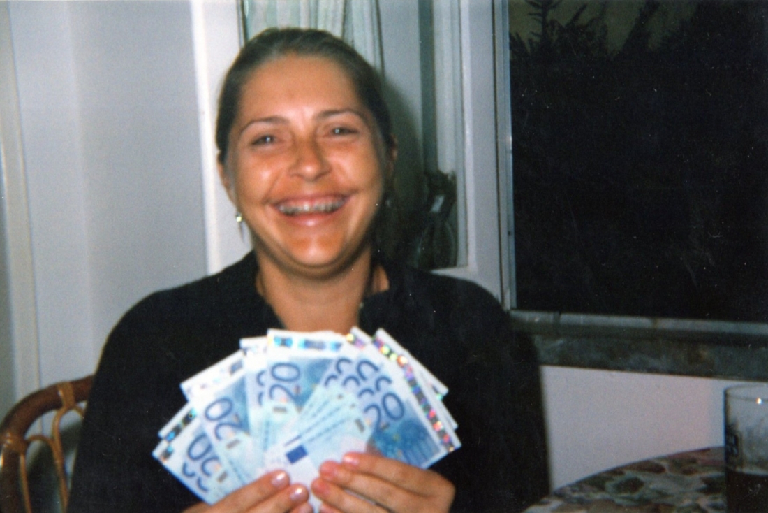 Uma mulher sorri, exibindo várias notas de 20 euros.