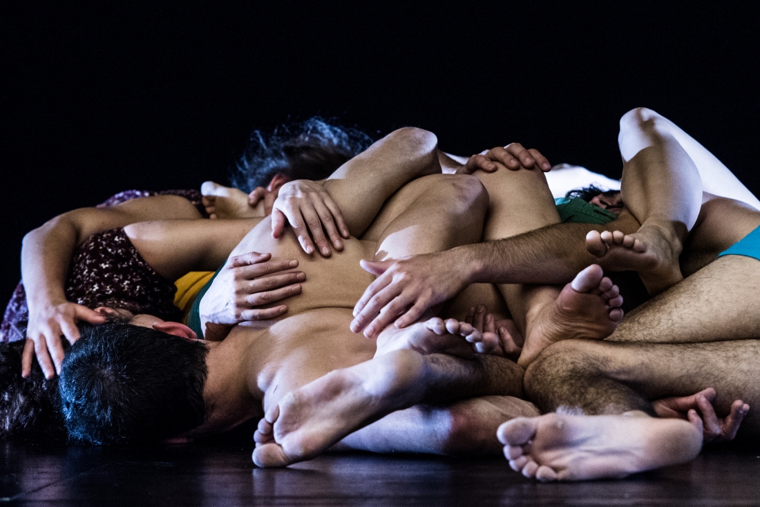 Several bodies lying on the ground, overlapping and intertwined. Their feet and hands are in evidence.