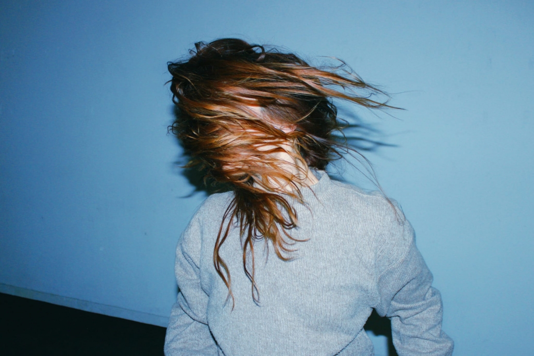 Retrato a cores de Margarida Monteny com o cabelo ruivo e comprido a cobrir-lhe o rosto.