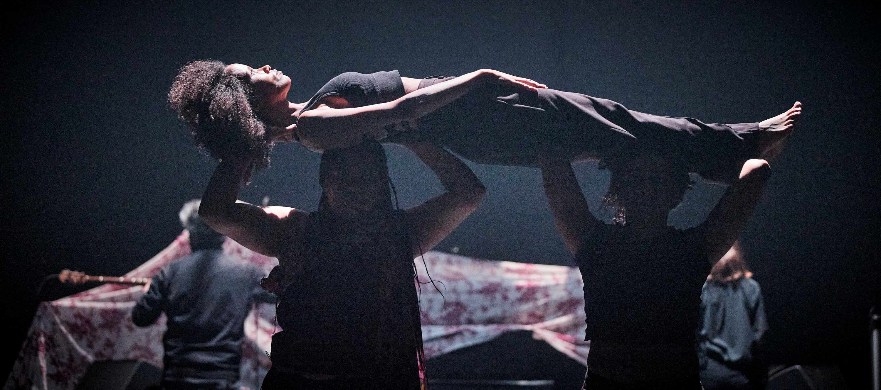 Two performers are holding a third performer horizontally.