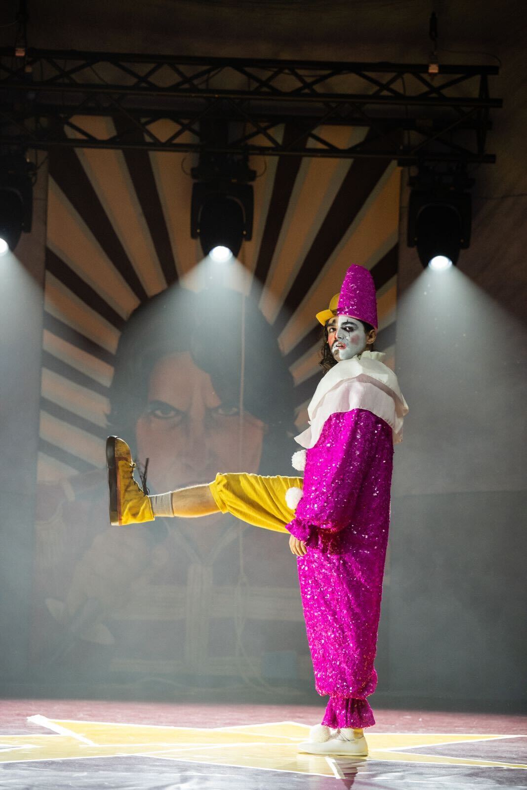 Illustration of a wrinkled face painted like that of a clown, leaning on their hands.