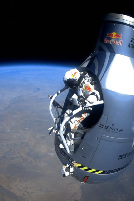 Colour photograph. In space, an astronaut prepares to launch from a space capsule toward Earth.